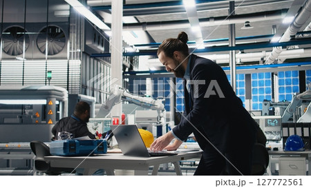 Executive consultant oversees solar energy systems in industrial workplace, emphasizing strategic planning for sustainable energy development. Innovation in clean power production line. Camera A. Executive consultant oversees solar energy systems in industrial workplace, emphasizing strategic planning for sustainable energy development. Innovation in clean power production line. Camera A. 127772561