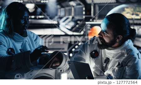 Researchers in starship discussing mission plan during mankind survival expedition. Astronauts doing human expansion in space mission in spacecraft, advancing scientific knowledge 127772564