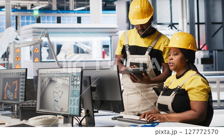 African american team of employees doing quality control on pc, troubleshooting and fixing technical issues for solar panel production at the factory. Coworkers inspecting system. Camera A. 127772570