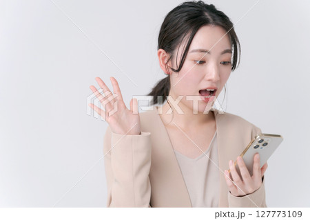 スマホを持って驚く女性 127773109