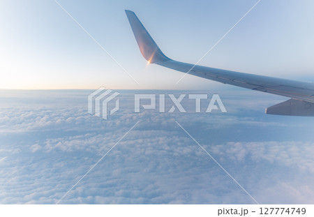 Beautiful salmon dawn and the wing of an airplane above the clouds. 127774749