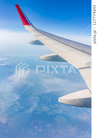 View from the airplane window at a beautiful cloudy sky and the airplane wing 127774845