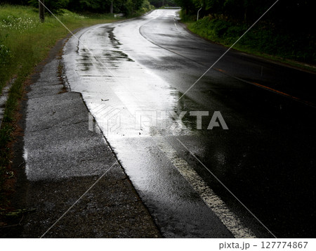 雨に濡れて光る曲がり道のアスファルト   127774867