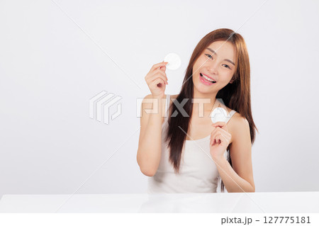 Cotton double use she wipes with a cotton pad while preparing another, her skin glows through her smile, showing beauty, cleanliness, and gentle facial care in action. isolated studio white background Cotton double use she wipes with a cotton pad while preparing another, her skin glows through her smile, showing beauty, cleanliness, and gentle facial care in action. isolated studio white background 127775181