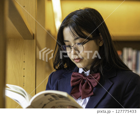 図書室で静かに本を読む眼鏡の女子学生 127775433