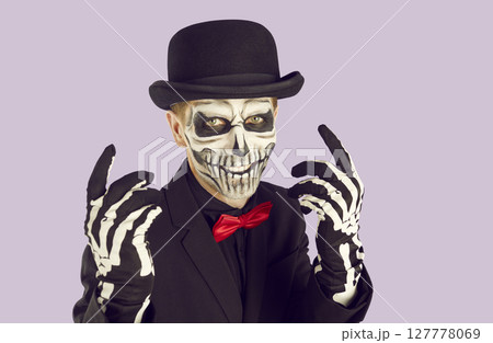 Portrait of man with scary skull makeup holding pumpkin Portrait of man with scary skull makeup holding pumpkin 127778069