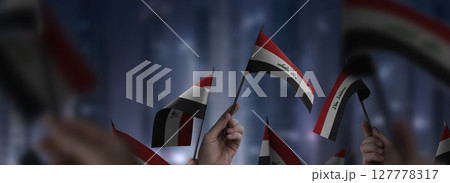 Iraq flags in their hands on a blurred urban background 127778317
