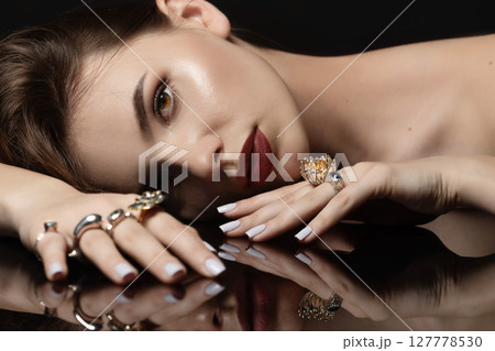 Studio portrait of beautiful and sexy brunette woman with fancy make-up and various rings on her fingers Studio portrait of beautiful and sexy brunette woman with fancy make-up and various rings on her fingers 127778530