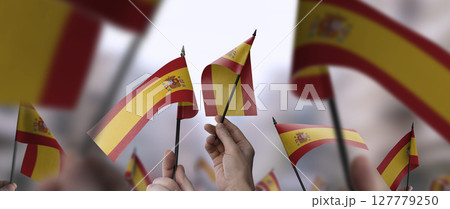 Spain flags in their hands on a blurred urban background 127779250