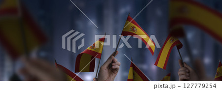 Spain flags in their hands on a blurred urban background 127779254