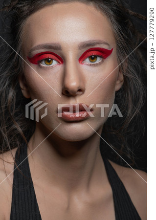 Studio portrait of beautiful woman with red eye shadows and dreadlocks 127779290