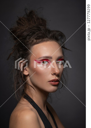Studio portrait of beautiful woman with red eye shadows and dreadlocks Studio portrait of beautiful woman with red eye shadows and dreadlocks 127779299