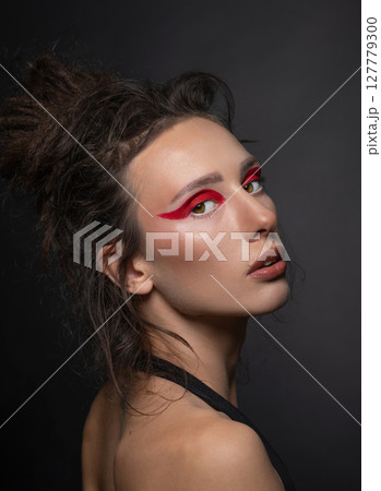 Studio portrait of beautiful woman with red eye shadows and dreadlocks 127779300