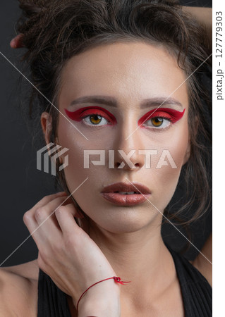 Studio portrait of beautiful woman with red eye shadows and dreadlocks 127779303