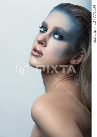 Beautiful woman with fancy make-up and naked shoulder studio portrait 127779634