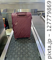 red Suitcase on Airport Baggage Claim Conveyor Belt 127779869