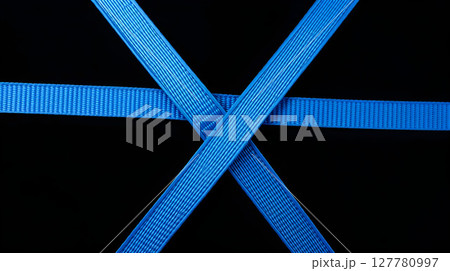 Abstract composition featuring overlapping blue straps, geometric shapes, and a striking black background 127780997