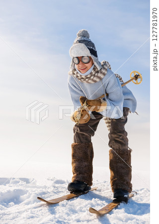Child is skiing on old skis from a hillside. 127781970