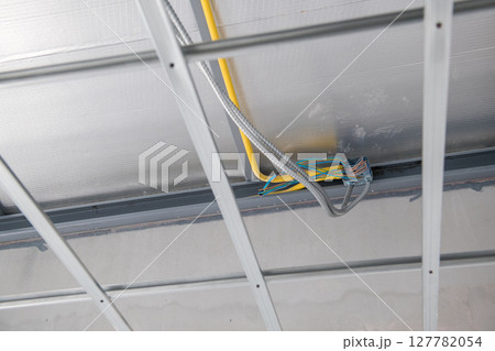 Interior renovation showing electrical wiring and aluminium ceiling framework installation. meticulous construction highlights grid and junction box for new building 127782054