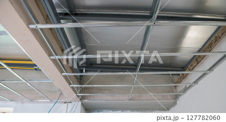 Interior renovation showing electrical wiring and aluminium ceiling framework. installation is part of major remodeling project leaving raw industrial feeling of being under construction Interior renovation showing electrical wiring and aluminium ceiling framework. installation is part of major remodeling project leaving raw industrial feeling of being under construction 127782060