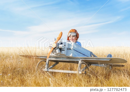 Little boy is playing the plane. 127782473