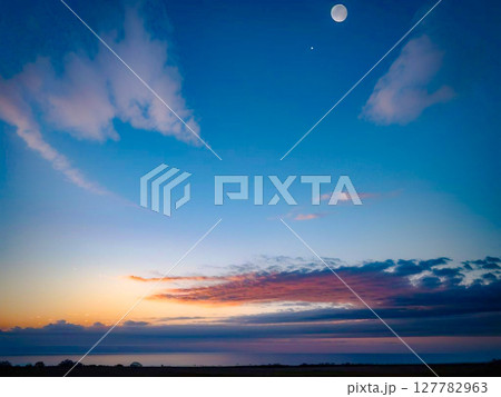 月が浮かぶ夕焼け空、地平線まで広がる雲の景色2 月が浮かぶ夕焼け空、地平線まで広がる雲の景色2 127782963