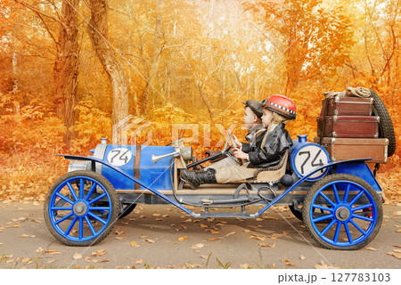 Young racer and mechanic riding an old race car 127783103