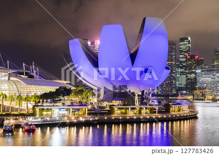 Night view of the Art Science Museum in Marina Bay, Singapore, with a skyscraper building background. The museum features major exhibitions that blend art, science, culture, and technology. 127783426