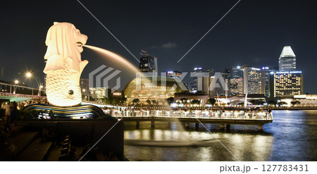 Night view of the Merlion with the background of modern skyscrapers in Marina Bay, Singapore. The Merlion is the official mascot of Singapore. Night view of the Merlion with the background of modern skyscrapers in Marina Bay, Singapore. The Merlion is the official mascot of Singapore. 127783431