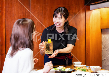 居酒屋　飲み物をお客さんに提供する女性スタッフ 127784926