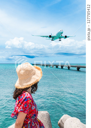 17エンド　頭上スレスレを通る旅客機と若い女性 127785412