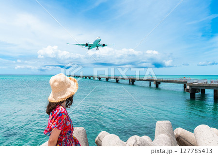 17エンド　頭上スレスレを通る旅客機と若い女性 127785413