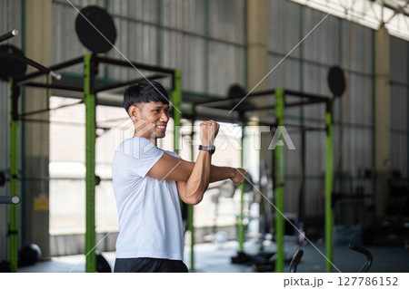 Strength and Flexibility. Young man stretching after workout in gym. 127786152