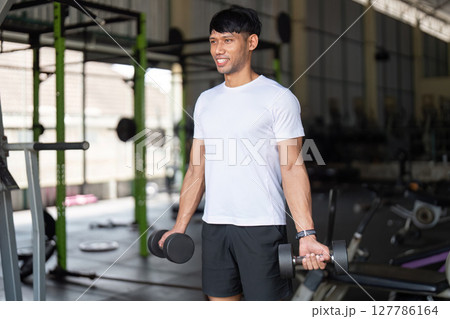Fitness and Performance. Young man exercising with dumbbells in gym. 127786164