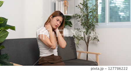 Neck Pain Awareness. Young woman experiencing neck discomfort while sitting. 127786222