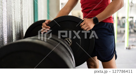 Weightlifting and Fitness. Man adjusting weights in the gym, focusing on strength training. 127786411