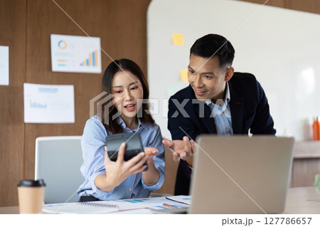Digital Transformation in Business. Colleagues discussing data insights on a smartphone. 127786657