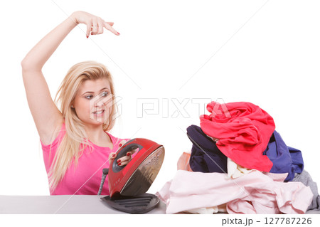 Bored woman pointing at clothes to iron Bored woman pointing at clothes to iron 127787226