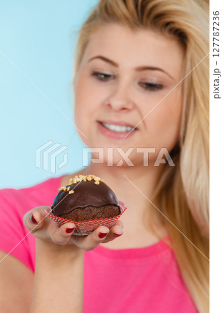 Woman holding chocolate cupcake about to bite 127787236