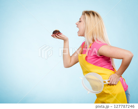 Woman holding chocolate cupcake about to bite 127787246