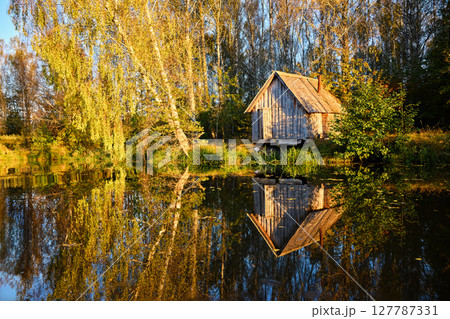 Tranquil Reflections: House and Trees Mirrored in River 127787331