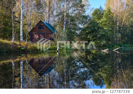 Tranquil Reflections: House and Trees Mirrored in River 127787339