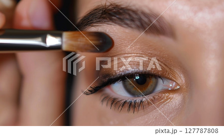 A makeup artist skillfully applies eye shadow, showcasing delicate precision and artistry. 127787808