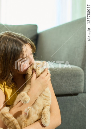 Teen girl with Scottish Fold cat enjoying a relaxed moment at home in natural light 127788057