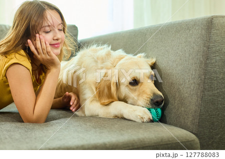 Teen girl enjoys playtime with her golden retriever in a cozy living room setting Teen girl enjoys playtime with her golden retriever in a cozy living room setting 127788083