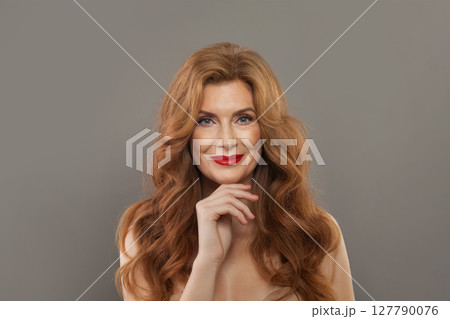 Studio portrait of mid aged mature woman looking at camera and smiling. \ Studio portrait of mid aged mature woman looking at camera and smiling. \ 127790076