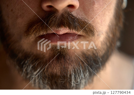 Close-up view of man's lips with thick beard and mustache Close-up view of man's lips with thick beard and mustache 127790434