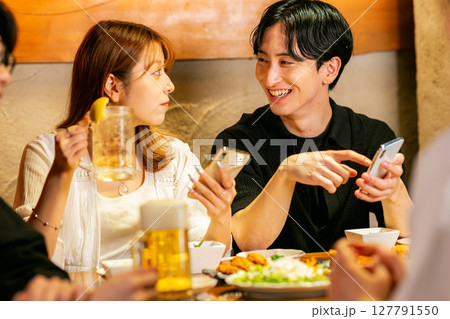 居酒屋でスマホを見る男女 居酒屋でスマホを見る男女 127791550
