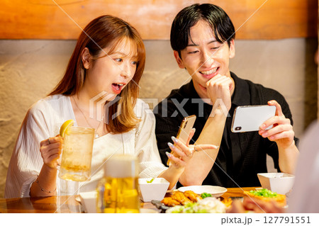 居酒屋でスマホを見る男女 居酒屋でスマホを見る男女 127791551