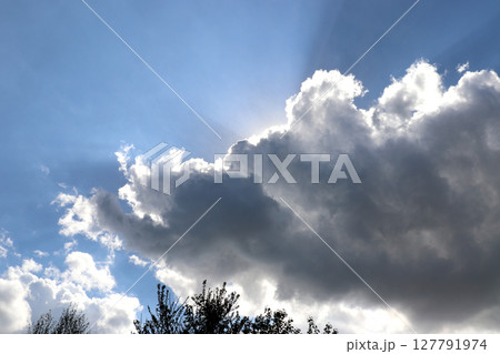 clouds blocking sun- sunlight from behind clouds over tree tops 127791974